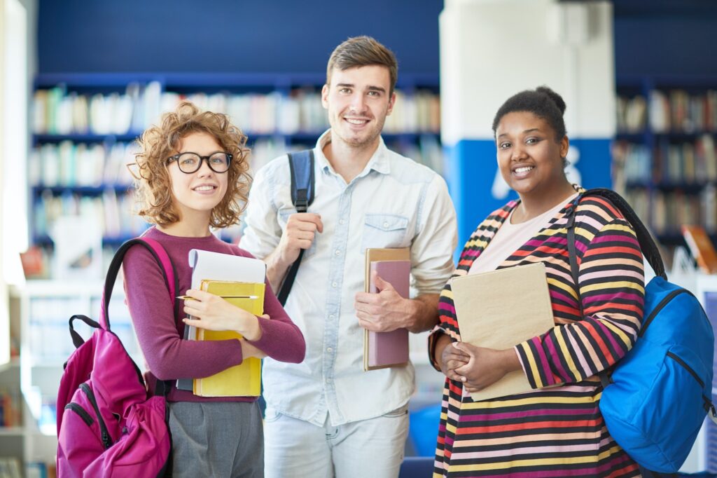 Happy students with books in library