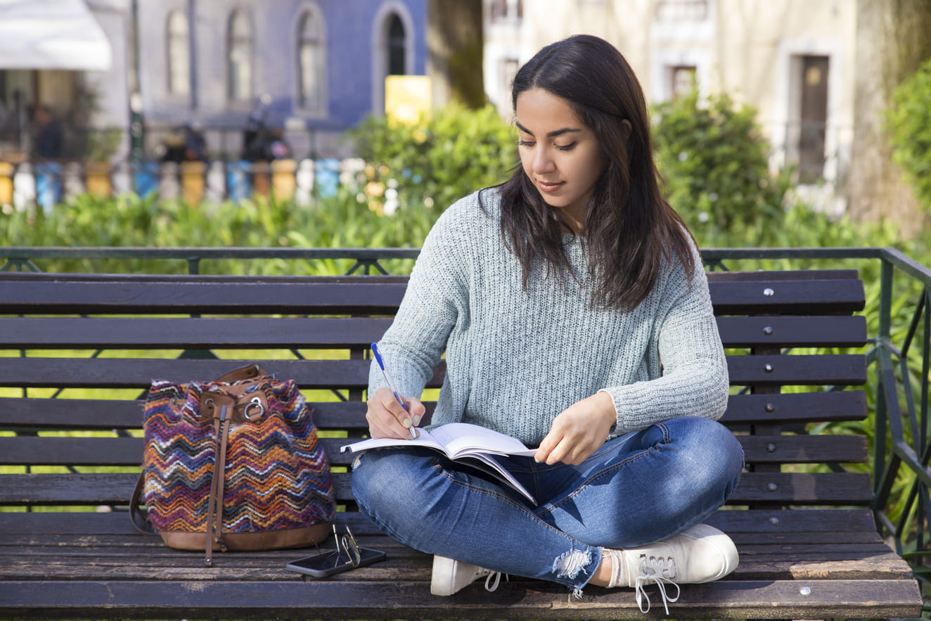 serious-woman-making-notes-sitting-bench-outdoors