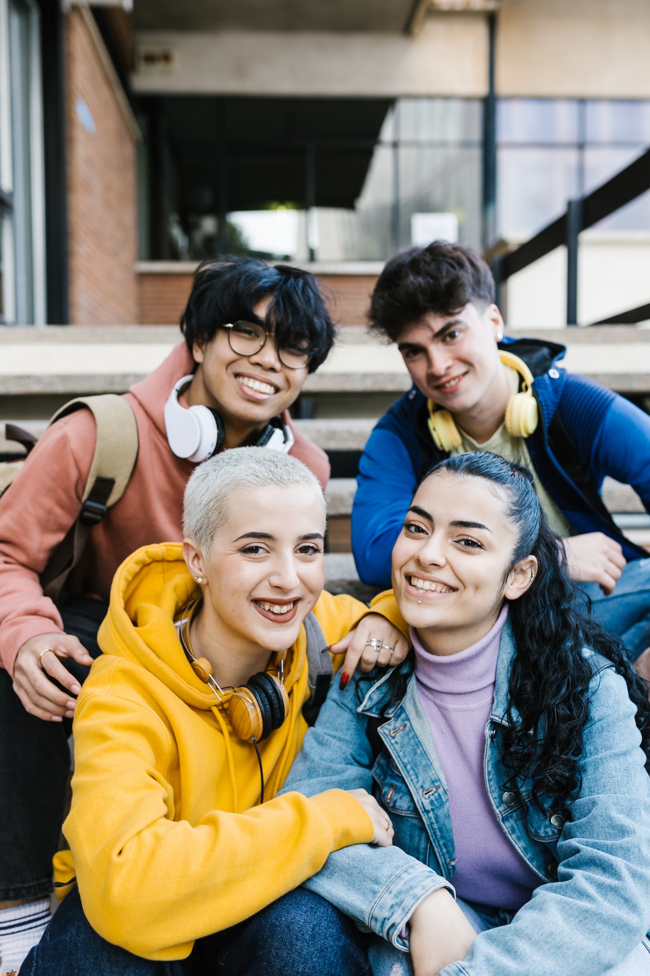 Vertical shot of multiracial young students sitting at school building entrance